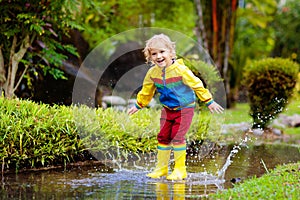 Child playing in puddle. Kids jump in autumn rain