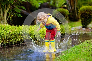 Child playing in puddle. Kids jump in autumn rain photo