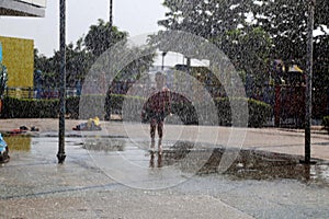 Child playing in the rain falling in the water park