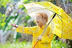 Child playing in the rain. Kid with umbrella