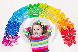 Child playing with rainbow plastic blocks toy