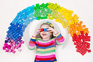 Child playing with rainbow plastic blocks toy