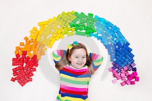 Child playing with rainbow plastic blocks toy