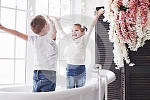 Child playing with rose petals in home bathroom. Little girl and boy fawing fun and joy together. The concept of