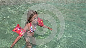 Child Playing in Sea Water on Beach, Kid Plays on Seashore, Blonde Little Girl with Swimming Life Buoy Enjoying Waves on Coastline
