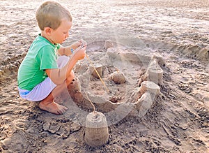 Child playing on the shore of the beach to build sandcastles, enjoying their summer vacations in the sea
