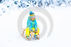 Child playing in snow on sleigh in winter park