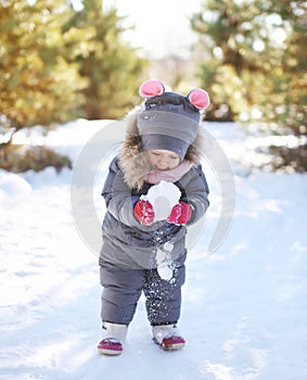 Child playing with snow in winter day