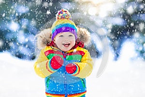 Child playing with snow in winter. Kids outdoors.