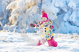 Child playing with snow in winter. Kids outdoors.