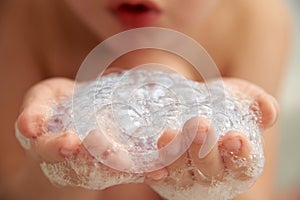 A child is playing with soap suds in the bathroom