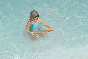 Child playing with starfish in azure crystal clear tranquil ocean