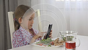 Child Playing Tablet, Kid Use Smartphone Eating Eggs, Salad Lettuce at Breakfast photo