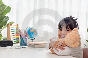 Child playing with teddy bear. Asian little girl hugging his favorite toy. Kid and stuffed animal at home