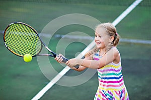Child playing tennis on outdoor court photo