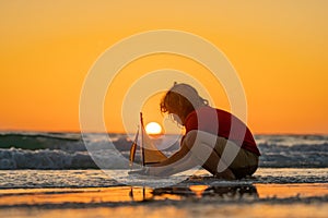 Child playing with a toy boat. Little kid boy sailing toy ship on sea water. Summer vacation with kids. Kid dreaming