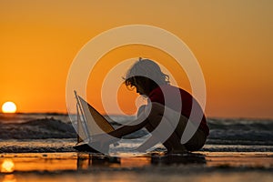 Child playing with a toy boat. Little kid boy sailing toy ship on sea water. Summer vacation with kids. Kid dreaming