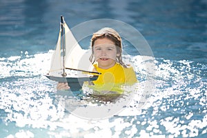 Child playing with a toy boat. Little kid boy sailing toy ship on sea water. Summer vacation with kids. Kid dreaming