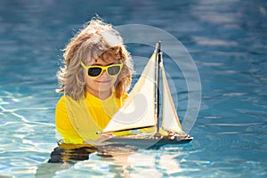 Child playing with a toy boat. Little kid boy sailing toy ship on sea water. Summer vacation with kids. Kid dreaming