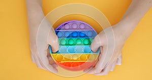 Child is playing trendy popular board game anti-stress toy pop it. Multi-colored popular silicone anti-stress toy pop it