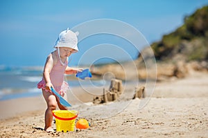 Child playing on tropical beach. Little girl digging sand and build a sand castle at sea shore. Kids play with sand toys. Travel