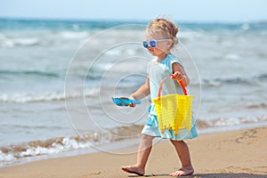 Child playing on tropical beach. Little girl digging sand at sea shore. Kids play with sand toys. Travel with young children