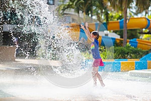 Child playing under tip bucket in water park