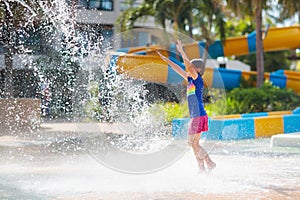 Child playing under tip bucket in water park