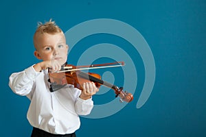 The child is playing the violin. Boy studying music.