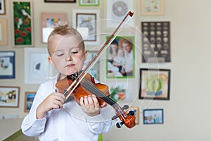 The child is playing the violin. Boy studying music.