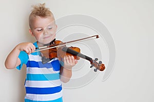 The child is playing the violin. Boy studying music.