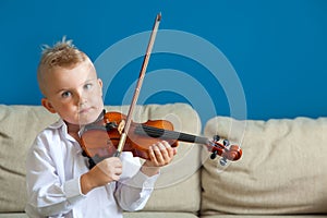 The child is playing the violin. Boy studying music.