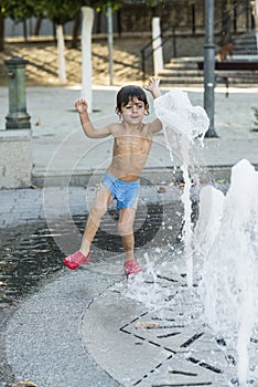 Child playing with water jets from a fountain