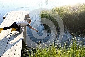 Child playing on wooden bridge by lake