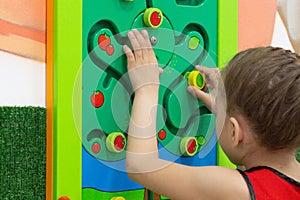 Child playing with wooden labirint in play center inside