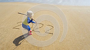 A child playing and writing on sand of seashore