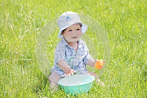 Child plays with a basin of water on the grass. Funny Baby Boy Playing Outside with Water and Bubbles. A cute baby boy is making a