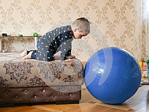 Child plays with a big blue ball. Developing motor skills. Baby plays