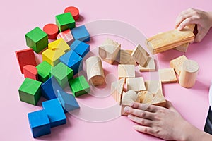The child plays collects wooden colored cubes constructor. Education concept for special children learning.