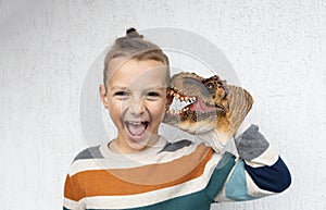 child plays with colorful toy Tyronosaurus dinosaur head, which funnyly bites the boy\'s ear