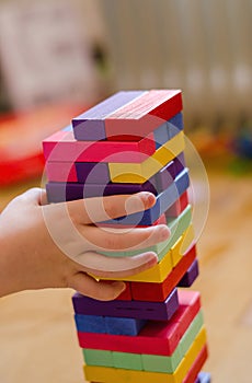 A child plays a game of wooden colored blocks, selective focus