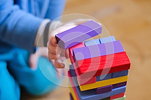 A child plays a game of wooden colored blocks, selective focus
