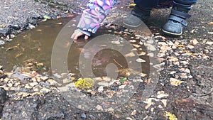 The child plays with his hands in a puddle. Rainy weather games outside
