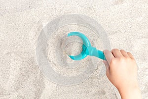 The child plays, manipulates with a shovel and rake with sea sand