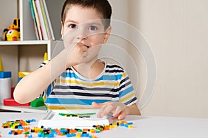 The child plays with mosaics, small objects for children, takes a small detail of the mosaic in his mouth. Danger of