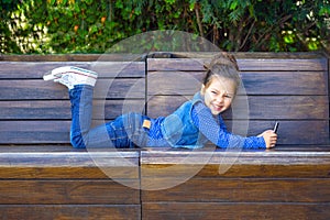 A child plays a phone and smiles in a cafe outdoors