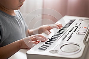 Child plays a piano keyboard. Boy learns to play the synthesizer