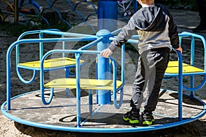 The child plays in the playground. The boy is swinging on a swing.