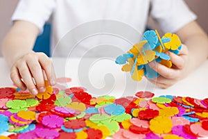 A child plays with a round colored mosaic. Game process close up. Hands close up