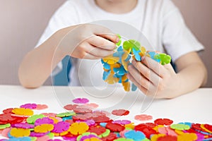 A child plays with a round colored mosaic. Game process close up. Hands close up. Quarantined home art